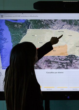 A person showing something on a map displayed on a screen.